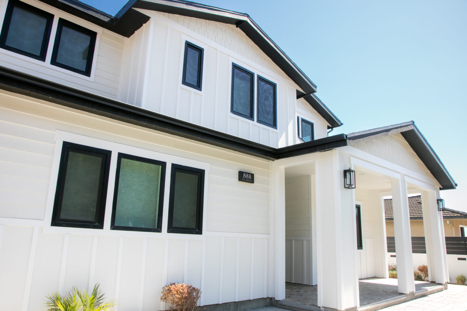 A white house with black windows and shutters.