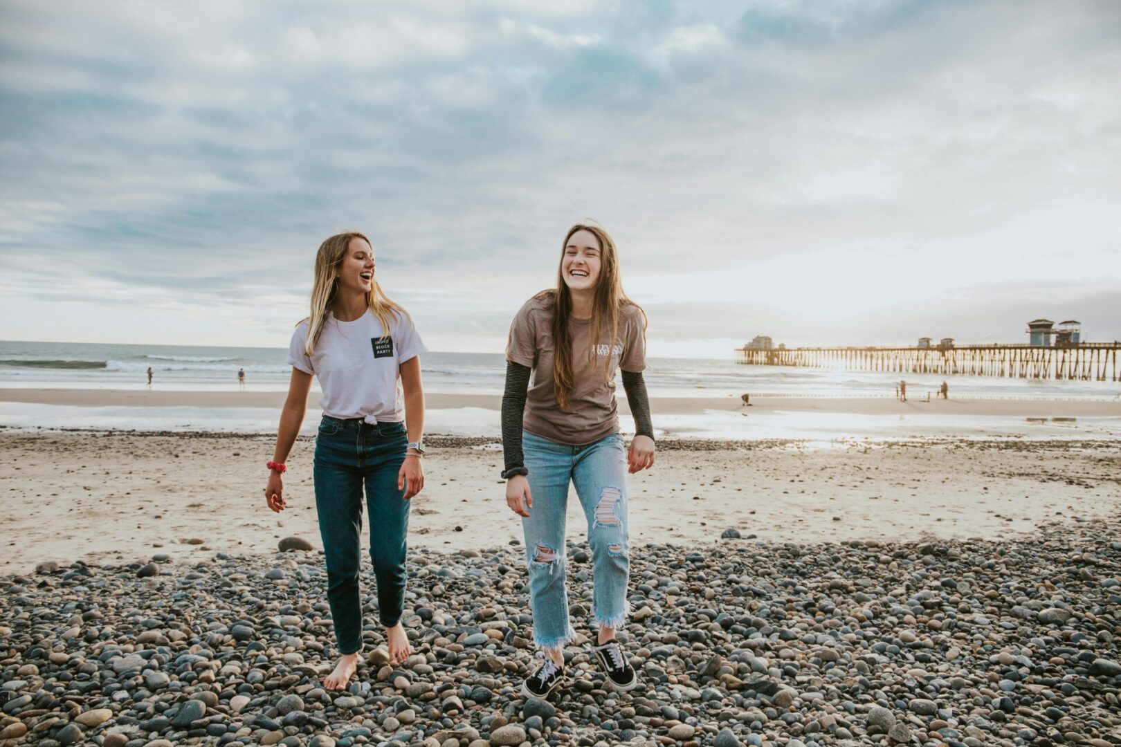 Two women standing on a beach near the ocean.