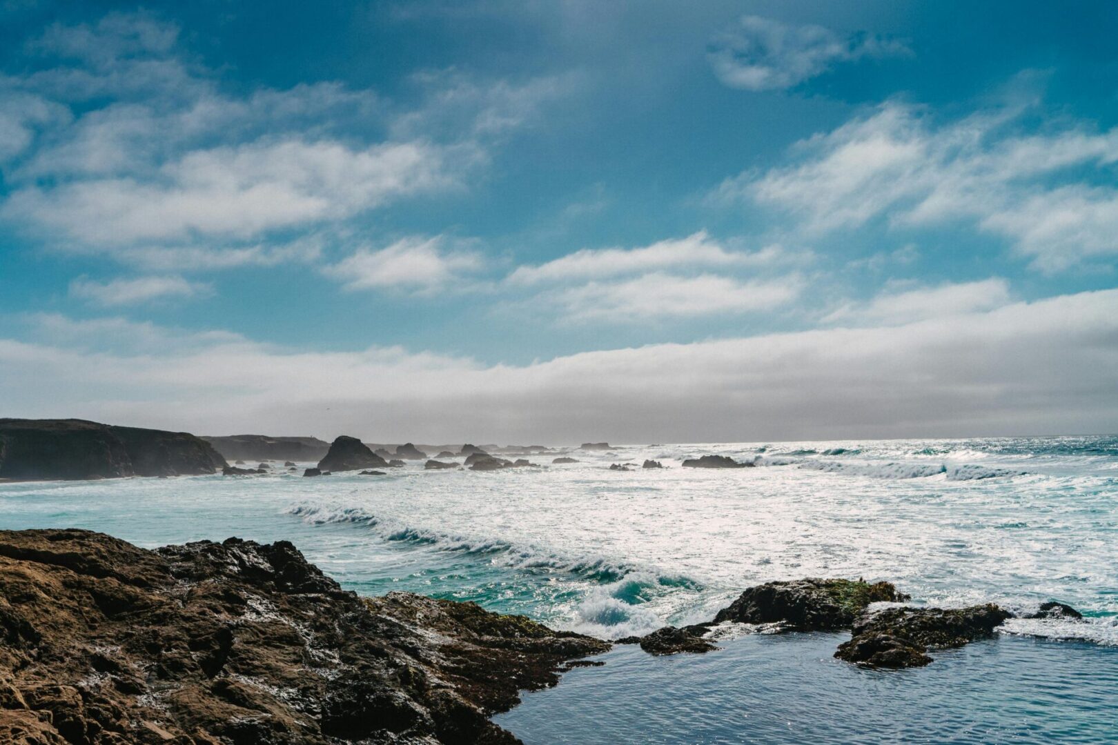 A body of water with rocks and waves in the background.